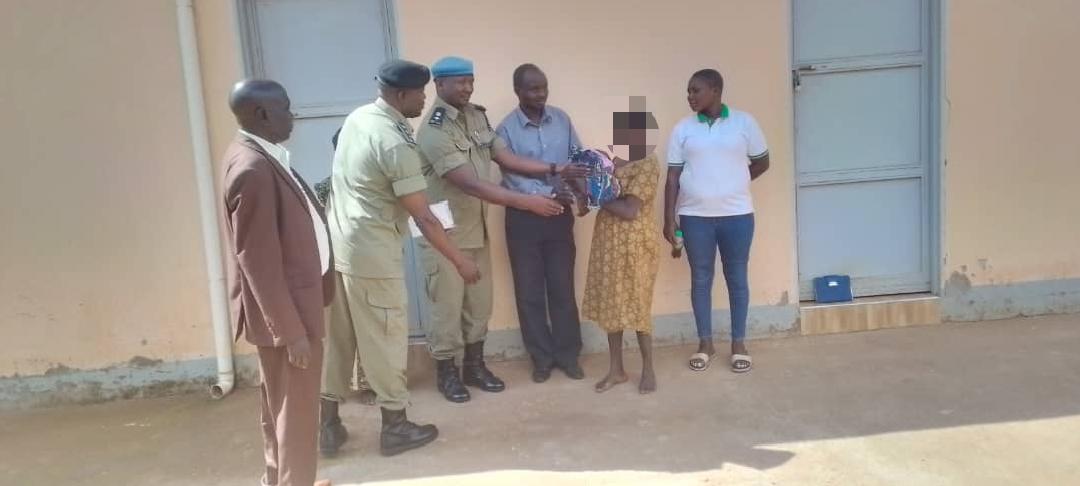 Zombo District Police Commander SP Denis Kamugisha, hands over the baby to the mother