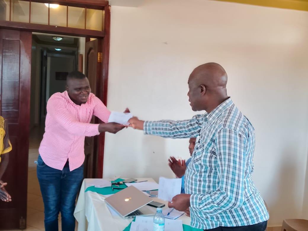 Zombo District CDO Samuel Ocaki hands over a dummy check of Ugx 40 million to the school leadership of Alube  primary school at Rest in hotel in Paidha town council.