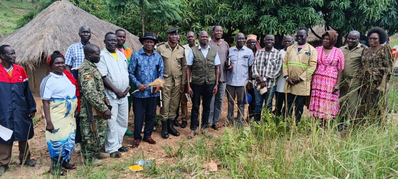 The Alur Kingdom Prime Minister (Jadipu), Prince Lawrence Opar Angala, holding the traditional fly-whisk, poses for a group photo with Nebbi District Deputy RDC Owachgiu Francis, Assistant RDC Olama Stephen Machodwogo, Assistant DISO Chotum Francis, and other stakeholders following a successful dispute resolution engagement.