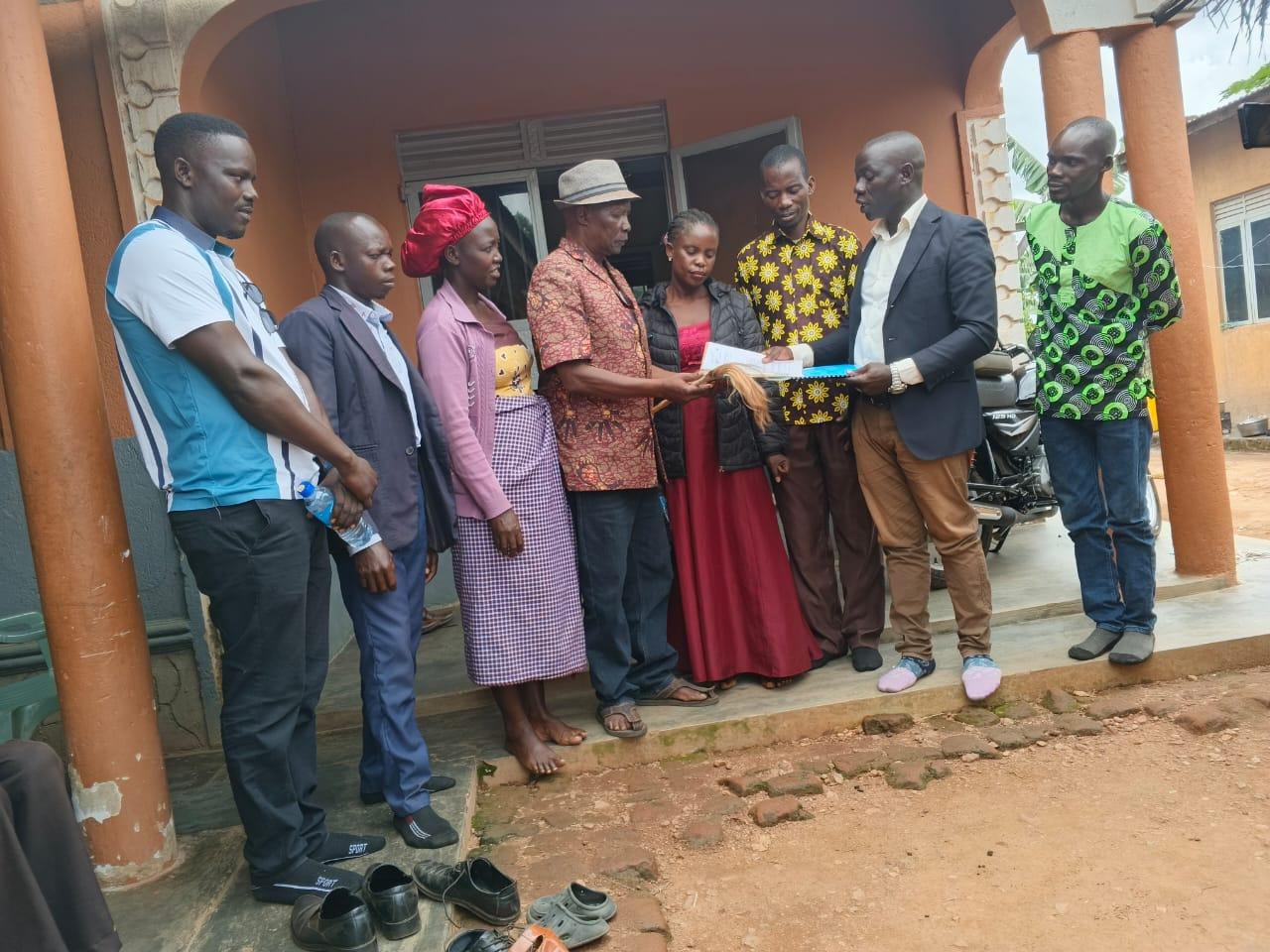 Cosma Omirambe, Executive Director of AFCE hands over the organization documents to the Kingdom Prime Minister Prince Lawrence Opar Angala as other members look on.