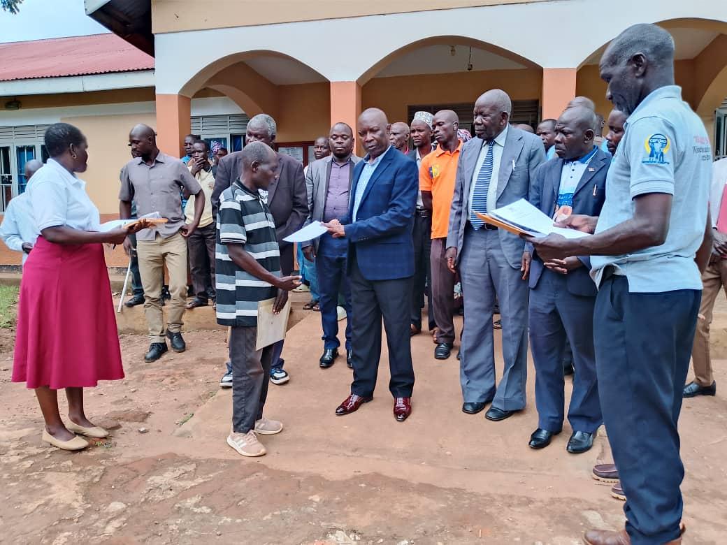 The Jadipu Prince Angala Opar (centre) handing over Certificates of Customary Land Ownership (CCLO) to the 35 beneficiaries that included widows and orphans. Assisting him is Life Concern ExecutiveDirector, Emmy Kizito Kakura (extreme right) as other stakeholders look on.